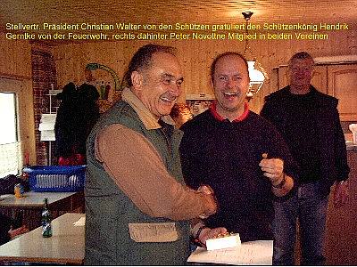 Stellvertr. Präsident Christian Walter von den Schützen gratuliert dem Schützenkönig Hendrik Gerntke von der Feuerwehr, rechts dahinter Peter Novottne, Mitglied in beiden Vereinen
